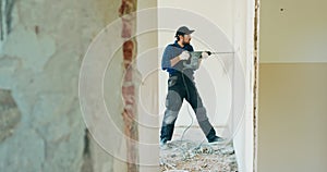 Portrait of a young man with an electric drill and making a hole in the wall. Interior design and home renovation