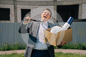 Portrait of a young man, a European, holding a box of office supplies, leaves the office building