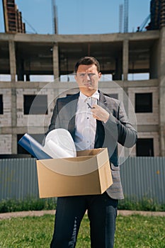 Portrait of a young man, European holding a box with things in his hands, leaving the office