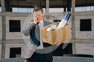 Portrait of a young man, European holding a box with things in his hands, leaving the office