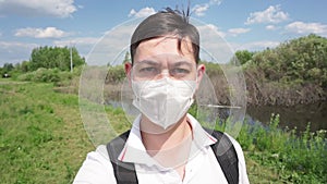 Portrait of young man face with medical mask stands at nature. close up,corona virus