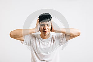 Portrait of a young man feeling stressed, covering his ears with his palms to