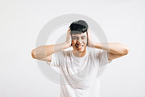 Portrait of a young man feeling stressed, covering his ears with his palms to