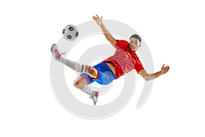 Portrait of young man, football player in motion, training, kicking ball in jump isolated over white studio background