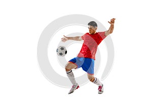 Portrait of young man, football player training, playing, kicking ball isolated over white studio background