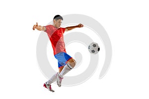 Portrait of young man, football player training, playing, kicking ball isolated over white studio background. Motivation