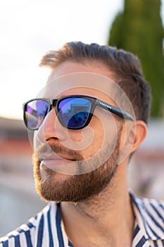 Portrait of a young man with glasses A sunlit day frames the confident gaze of a stylish young man, capturing his youthful charm