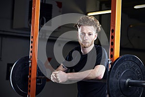 Portrait Of Young Man In Gym Lifting Weights On Barbell