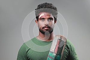 Portrait of a young man holding bat  with a bruised forehead