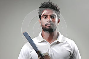 Portrait of a young man holding bat  with a bruised forehead