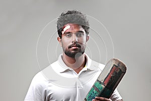 Portrait of a young man holding bat  with a bruised forehead