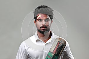 Portrait of a young man holding bat  with a bruised forehead