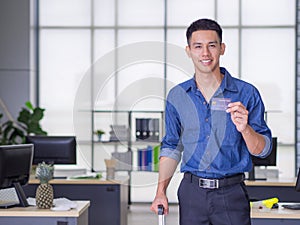 Portrait of a young man holding a blue card, wearing a blue casual shirt, and prepare for shopping online with a credit