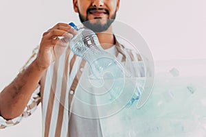 Portrait of young man holding recycling bin on white background