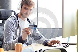 Portrait of a young man holds and using credit card for game money top up