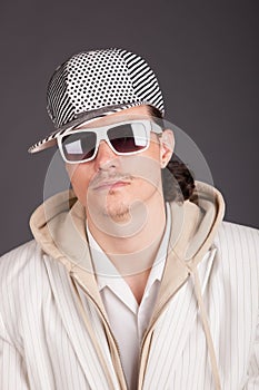 Portrait of a young man in the hood wearing shade on grey