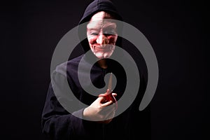 Portrait of young man with hoodie and horror mask holding scissors