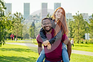 Portrait of young man hugging his girlfriend standing together on a spring summer park on a sunny day