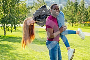 Portrait of young man hugging his girlfriend standing together on a spring summer park on a sunny day