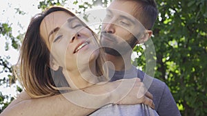 Portrait of young man hugging his girlfriend in sun light in the summer garden. Happy young family resting outdoors