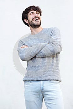 Young man laughing with arms crossed against white background