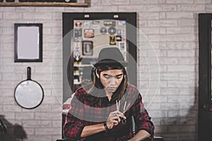 Portrait of young man with long hair and stylist barber sitting at barbershop chair