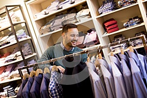 Portrait of a young man looking at clothes to buy at shop