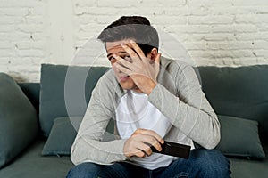 Portrait of a young man looking scared and shocked watching TV. Human expressions and emotions