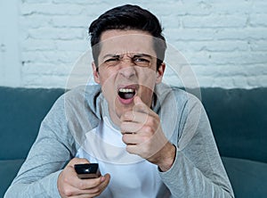 Portrait of a young man looking scared and shocked watching TV. Human expressions and emotions