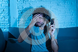 Portrait of a young man looking scared and shocked watching TV. Human expressions and emotions