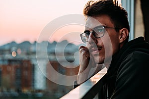 Portrait of a young man looking at sunset from a balcony