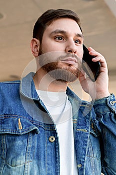 Portrait young man making call. Caucasian bearded business man have mobile conversation, talking by phone indoors
