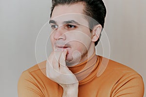 Portrait of a young man. The man covers his mouth with his hand