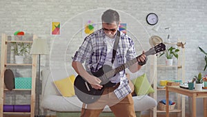 Portrait young man musician with glasses emotionally playing electric guitar