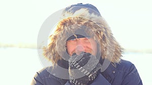 Portrait of young man outdoors freezing looking into the camera in winter sunny day. Close up