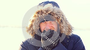 Portrait of young man outdoors freezing looking into the camera in winter sunny day. Close up