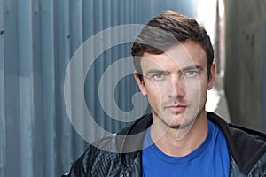 Portrait of young man outdoors with very handsome face in casual clothes against alley way urban background