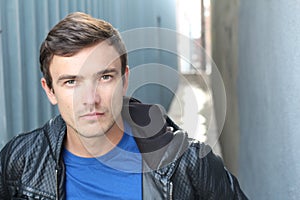 Portrait of young man outdoors with very handsome face in casual clothes against alley way urban background