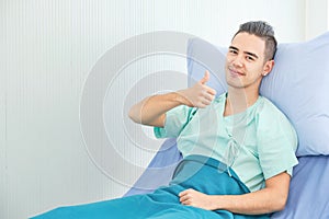 Portrait young man patient lying in hospital bed and pose thumb up with nice smile confident in the treatments process