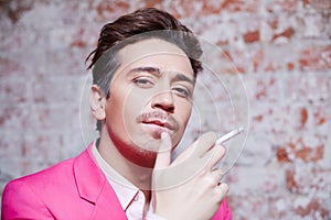 Portrait of young man in pink suit with cigarette