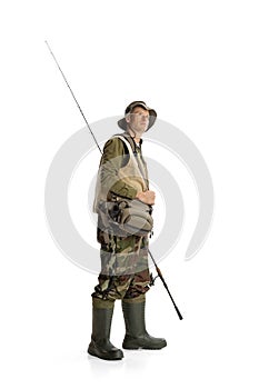 Portrait of young man, professional fishman with fishing rod, spinning and equipment going to river isolated over white