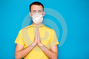 Portrait of young man in protective mask against coronavirus, doing pray gesture for health against corona virus is quickly