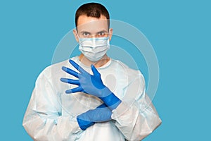 Portrait of young man in protective mask and protective suit puts on latex gloves against air pollution or transmissible