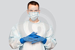 Portrait of young man in protective mask and protective suit puts on latex gloves against air pollution or transmissible