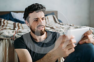 Portrait of a young man relaxing and watching a TV show on a tablet computer