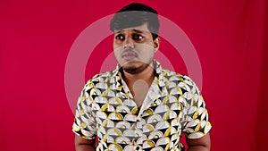 Portrait of a young man scared expression shocking frightening standing against a red background