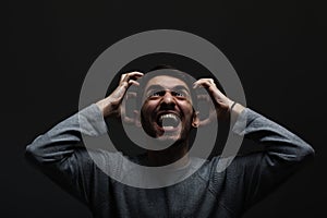 Portrait of young man screaming. Looking up in anger and making angry hand gestures