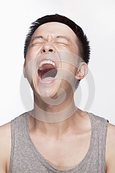 Portrait of young man screaming, mouth open, studio shot