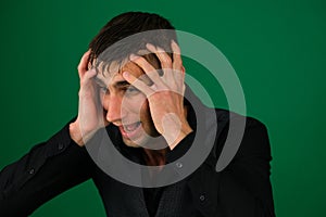 Portrait of a young man screaming out loud against emotions of a handsome man guy on a green background chromakey close
