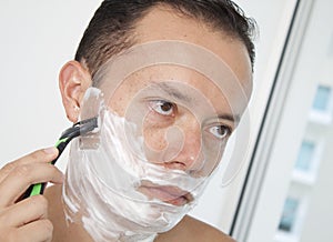 Portrait of a young man shaving his beard